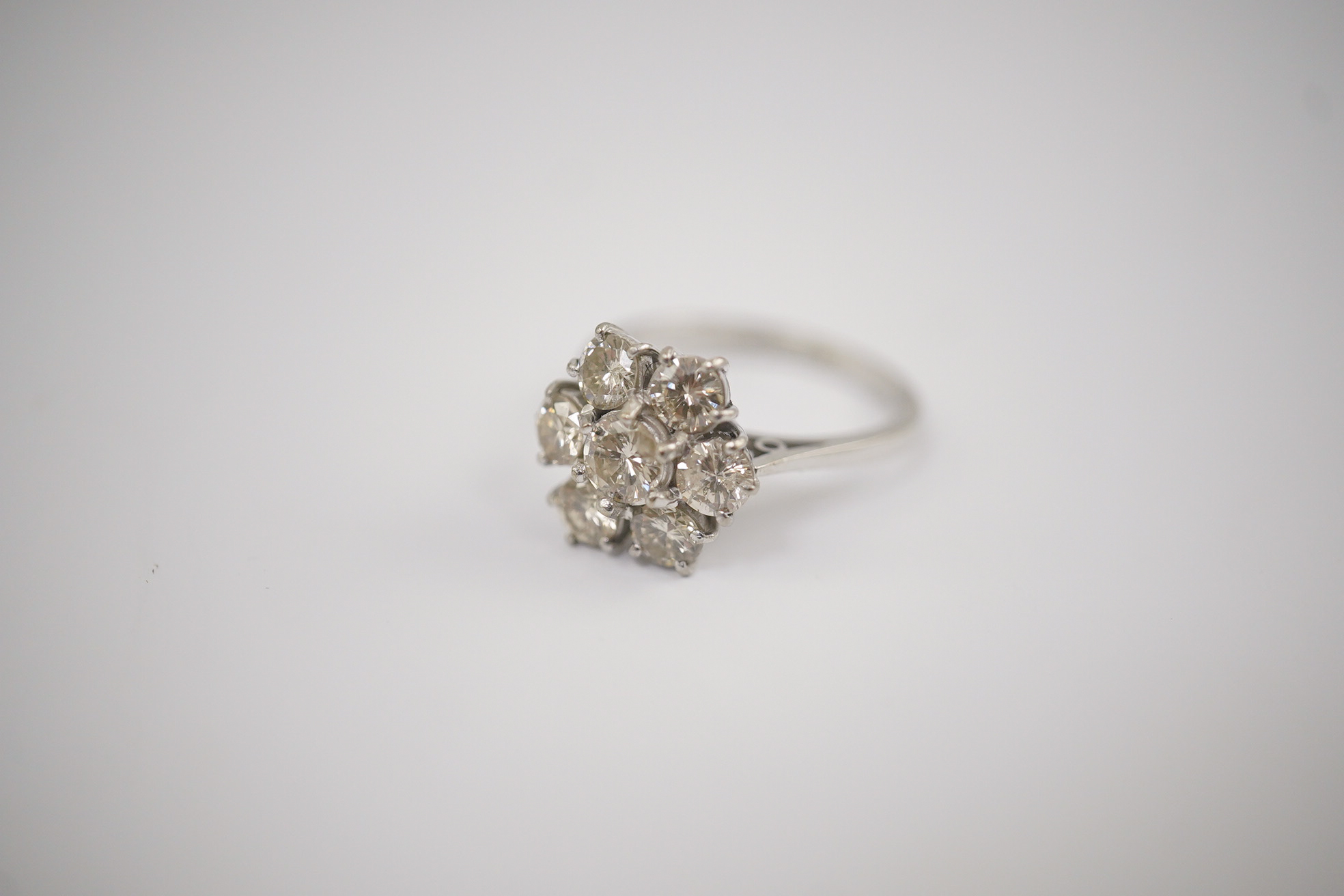 An 18ct white gold and seven stone diamond set flower head cluster ring